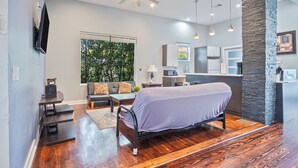 A modern living room with a bed, a dining area, and a kitchen.