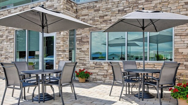 An outdoor patio with stone walls, large windows, and outdoor seating with umbrellas. - Fairfield Inn & Suites by Marriott Selinsgrove (Selinsgrove)