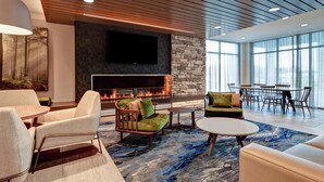 A modern lounge area with a fireplace, comfortable seating, and a large window providing natural light. - Fairfield Inn & Suites by Marriott Selinsgrove (Selinsgrove)