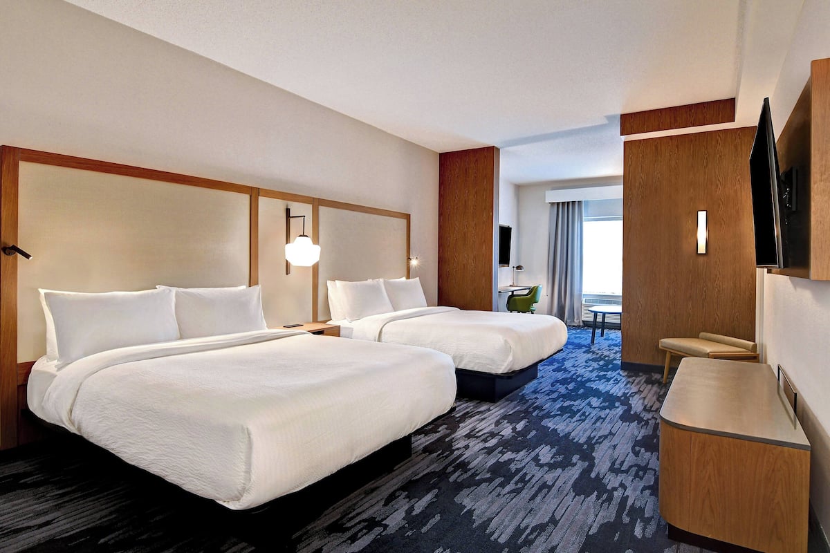 Ein Hotelzimmer mit zwei Betten, einem Schreibtisch, einem Fernseher und Blick ins Freie.