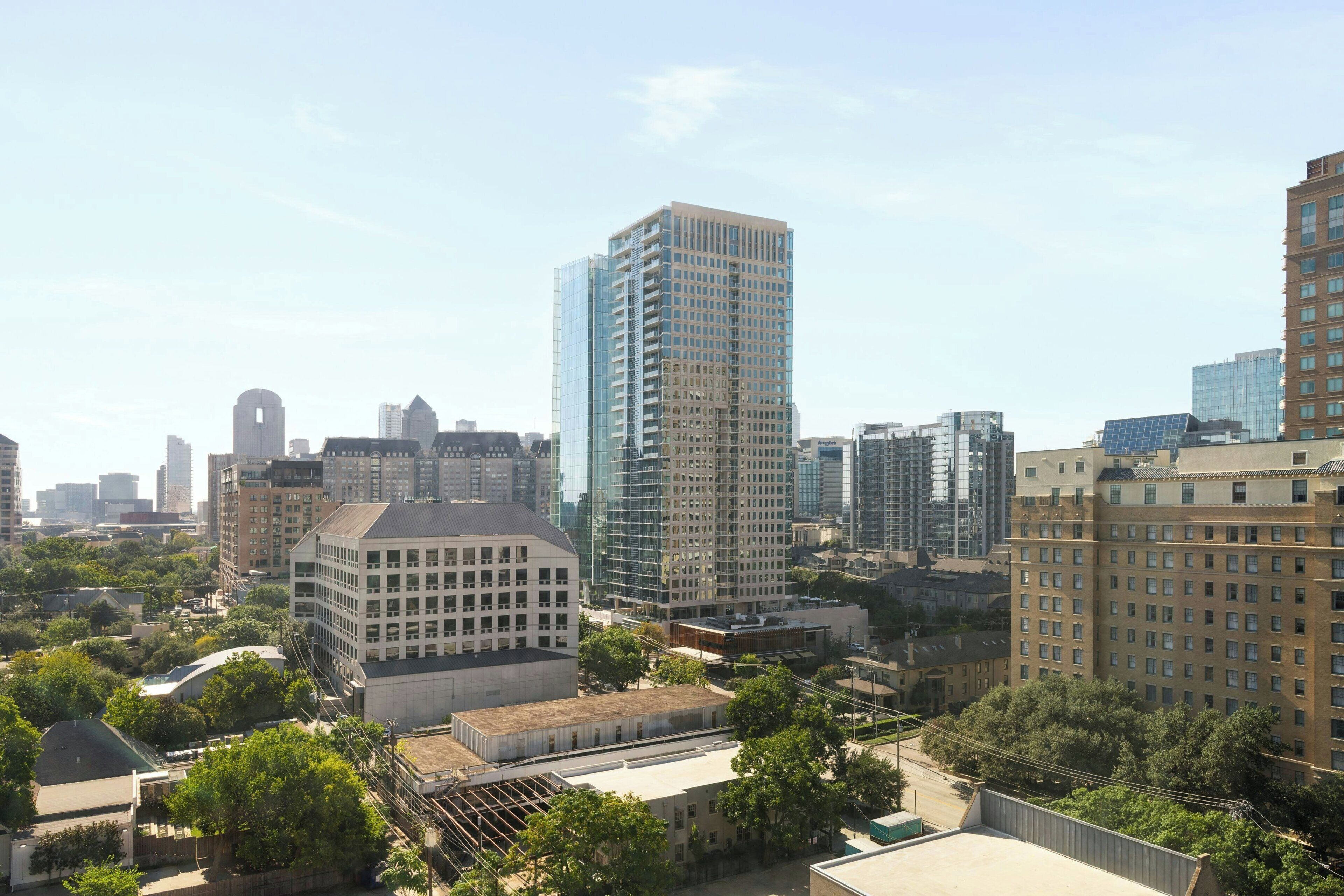 Un paisaje urbano con edificios modernos y altos, incluyendo un rascacielos de vidrio destacado.