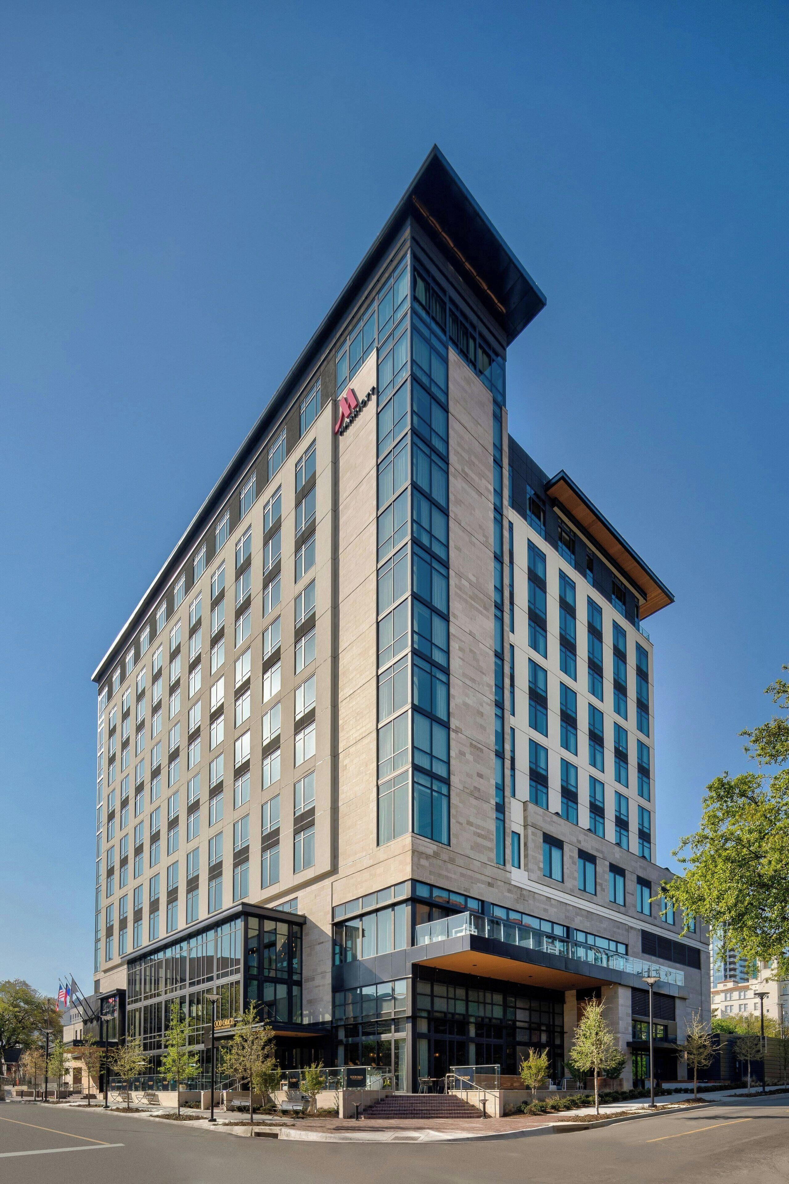 Un hôtel moderne, doté d’une entrée d’angle remarquable, de grandes fenêtres et d’un toit plat.