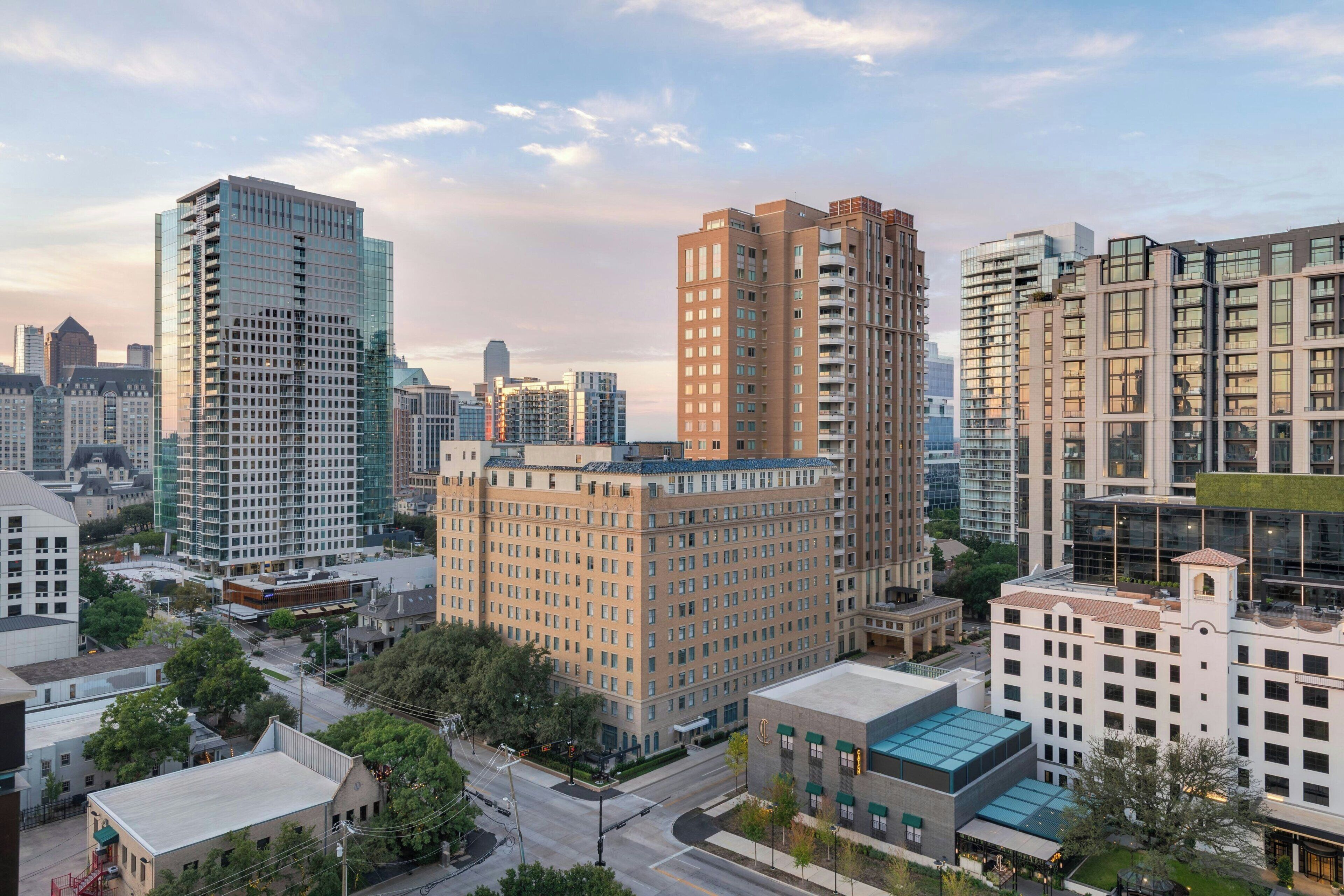Un paisaje urbano con modernos edificios de gran altura, un edificio antiguo central con tejado plano y una combinación de estructuras comerciales y residenciales.