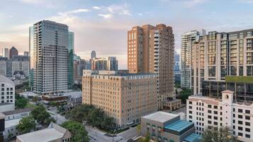 Un paisaje urbano con modernos edificios de gran altura, un edificio antiguo central con tejado plano y una combinación de estructuras comerciales y residenciales.
