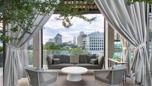 Un espacio lounge exterior moderno con un sofá, dos sillones y una mesa redonda.