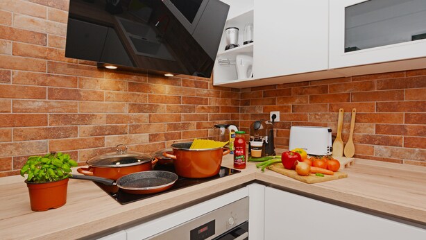 A kitchen with a brick backsplash, a stove, a microwave, and various cooking utensils and ingredients on the counter.