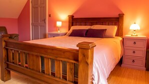 Un dormitorio con una cama de madera, dos mesitas de noche con lámparas, una puerta y una silla.