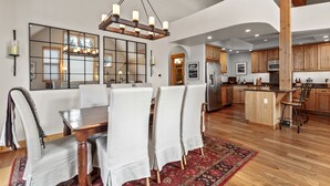 A spacious kitchen with wooden cabinets, a central island, and a dining area with a large table and chairs. - Peak 10 Place - Free Winter Shuttle to Lift - Ski-In, Ski-Out for Experts Only (Breckenridge)