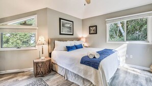 Ein Schlafzimmer mit Bett, Deckenventilator, Nachttisch, Fenster und einem gerahmten Bild an der Wand.