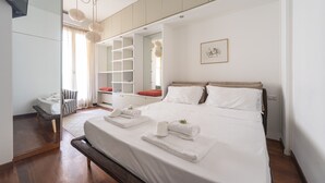 Une chambre d’hôtel moderne avec un grand lit, une table de chevet, une chaise, une armoire et un miroir.
