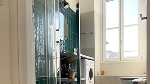 Une cuisine moderne dotée d’une grande fenêtre, d’un lave-linge et d’un évier.