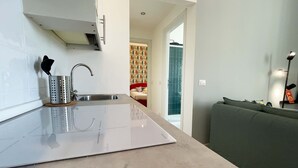 Une cuisine moderne équipée d’une cuisinière intégrée, d’un évier et d’un canapé vert dans le salon attenant.