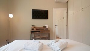 Une chambre d’hôtel avec un lit bien fait, un bureau avec une chaise, un téléviseur à écran plat et une armoire.