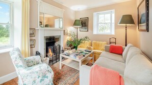 Un salon chaleureux avec une cheminée, un canapé, un fauteuil et une table basse.