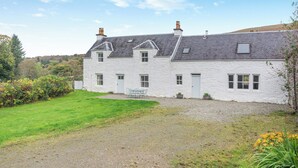 Une maison en pierre blanche avec une allée en gravier et une pelouse verdoyante.