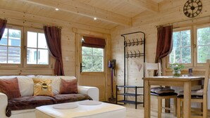 A cozy cabin interior with a white sofa, a wooden dining table, and a bench. - Brook Cottage - UK12643 (Sleights near Whitby)