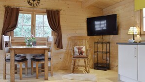 A wooden interior with a dining table, chairs, a television, and a kitchen area. - Brook Cottage - UK12643 (Sleights near Whitby)