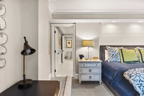 Une chambre à coucher comprenant un lit, une table de chevet, une lampe et une porte donnant sur une autre pièce.