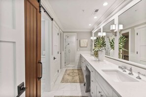 Une salle de bain moderne avec un grand miroir, un meuble-lavabo blanc et un espace douche.