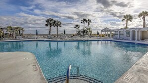 A swimming pool with a clear blue water, surrounded by palm trees and a pavilion. - Luxury Oceanfront Villa w/ Pool & Spa Hilton Head (Hilton Head Island)