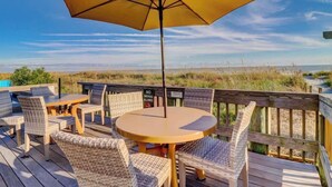 A wooden deck with wicker furniture, a round table, and a yellow umbrella. - Luxury Oceanfront Villa w/ Pool & Spa Hilton Head (Hilton Head Island)