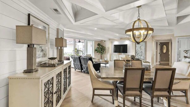 A spacious living room with a large dining table, comfortable seating, and a modern chandelier. - Luxury Oceanfront Villa w/ Pool & Spa Hilton Head (Hilton Head Island)