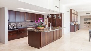 A modern kitchen with dark wood cabinets, a granite countertop, and pendant lighting.