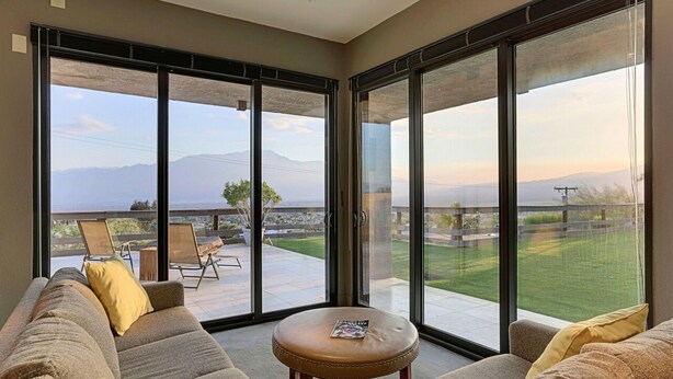A spacious living area with a large sliding glass door leading to a balcony with a view of mountains.