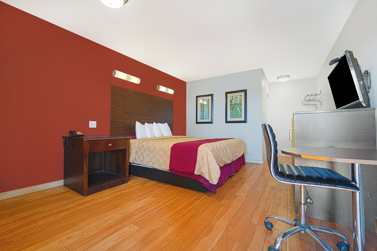 A hotel room with a bed, a desk, and a chair.