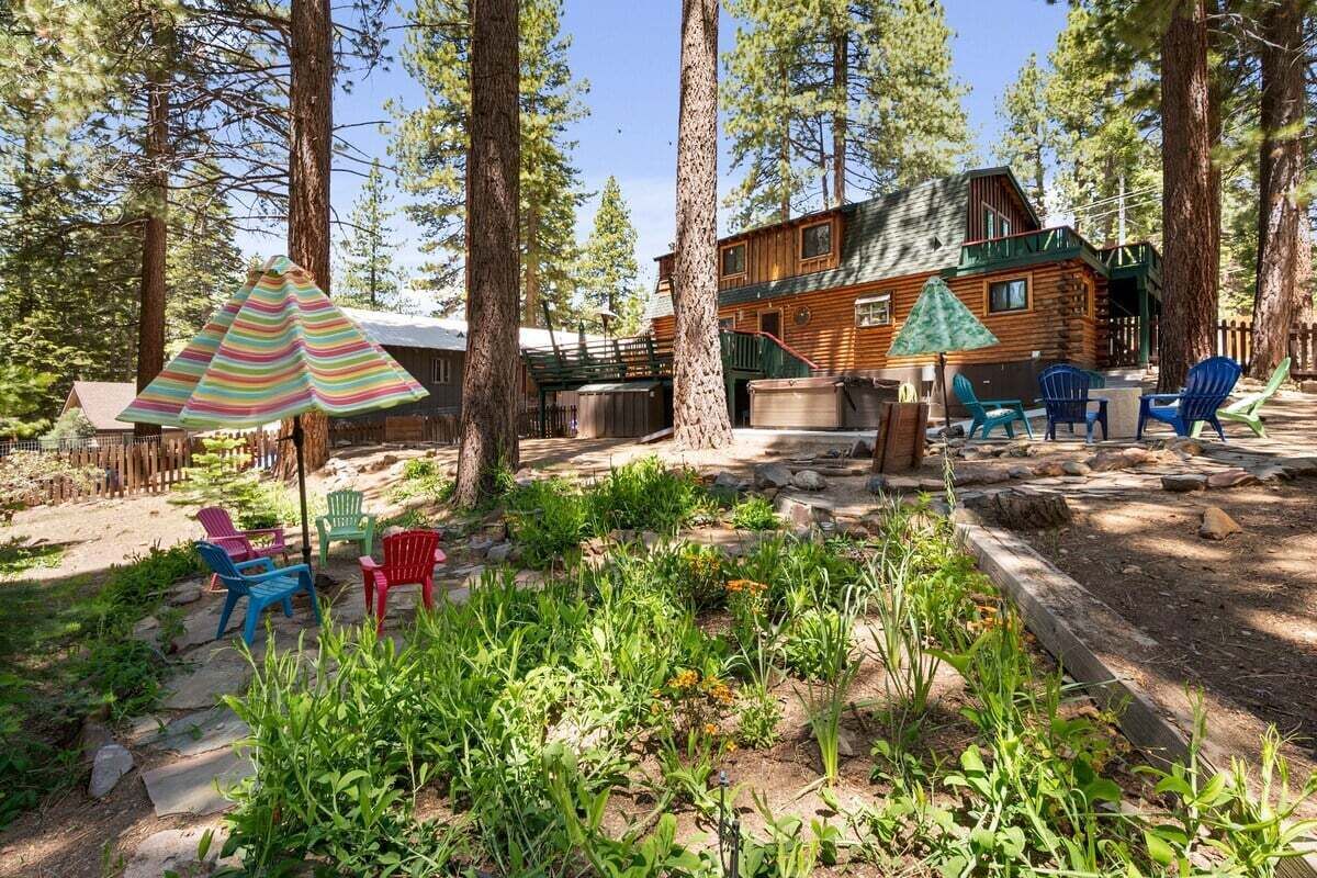 A cabin with a deck, surrounded by tall trees.