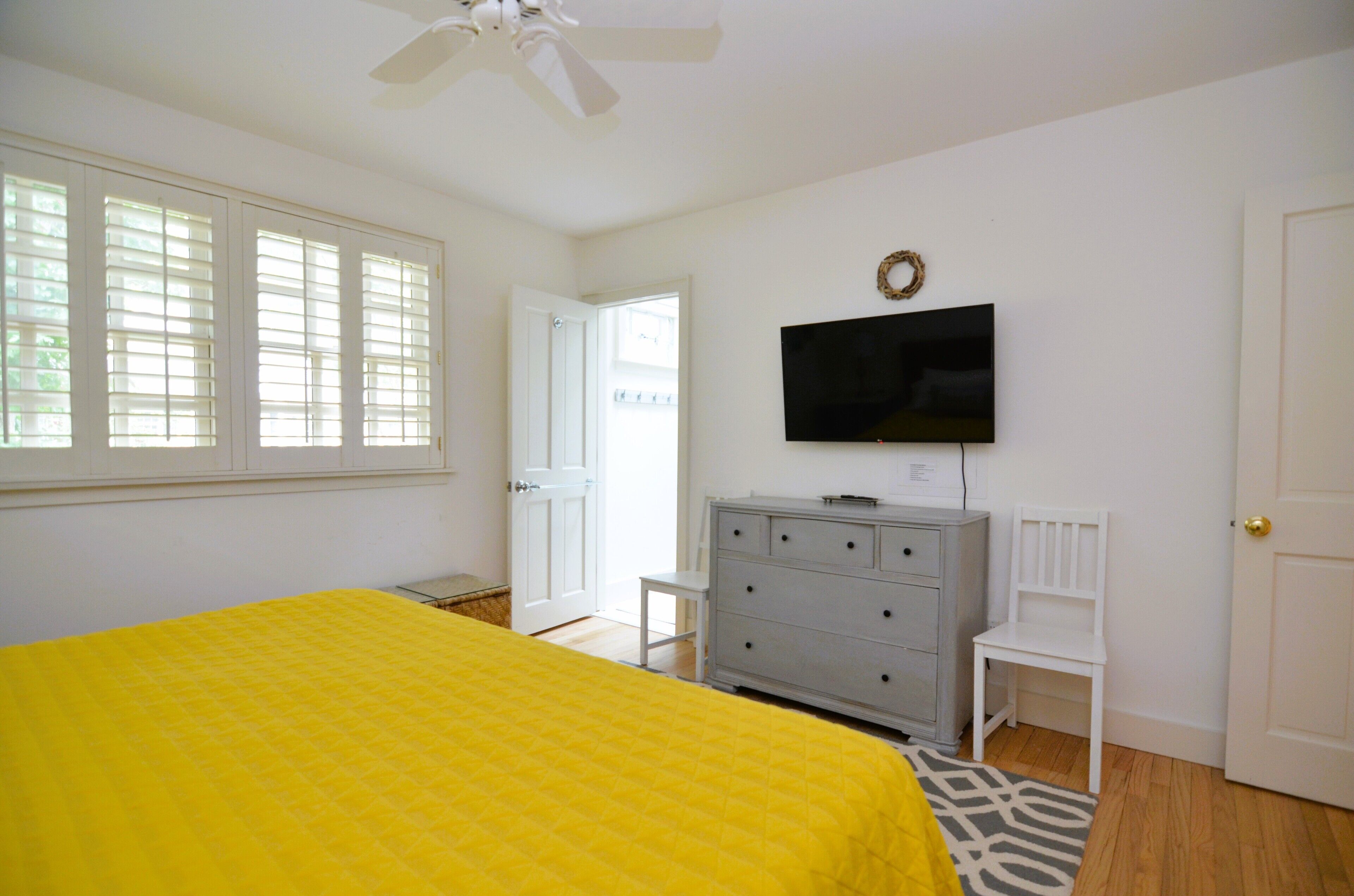 A bedroom with a bed, a dresser, a TV, and a door.