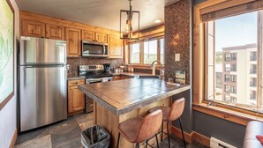 Una cocina moderna con armarios de madera, electrodomésticos de acero inoxidable y una isla grande con taburetes de bar.