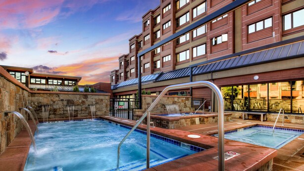 Un hotel con zona de piscina que incluye varios jacuzzis y una pared de piedra.