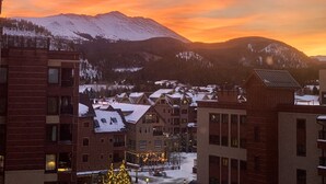 Un pueblo con edificios cubiertos de nieve y montañas al fondo durante la puesta de sol.