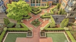 A multi-story residential building with a central courtyard featuring geometric landscaping and a large tree. - Cozy Belltown Condo with amazing Elliott Bay Views (Seattle)
