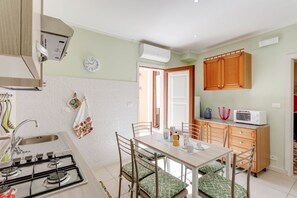 A kitchen with a gas stove, sink, wooden cabinets, and a dining area with chairs and a table.