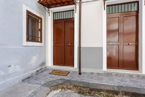 A building with two brown doors, a window with bars, and a tiled entrance.