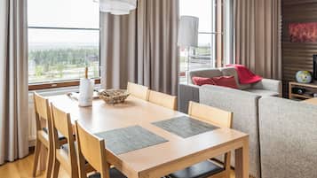 A modern living room with a dining table, chairs, a sofa, and a television.