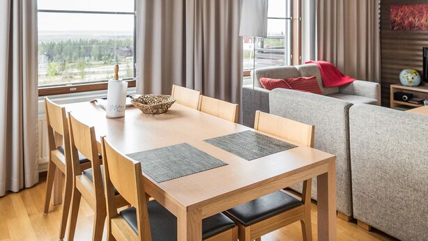 A modern living room with a dining table, chairs, a sofa, and a TV.