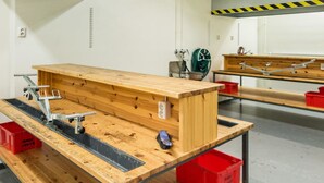 A workshop with a workbench, tools, and storage bins.