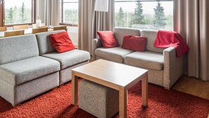 A modern living room with two grey sofas, a wooden coffee table, and a red carpet.