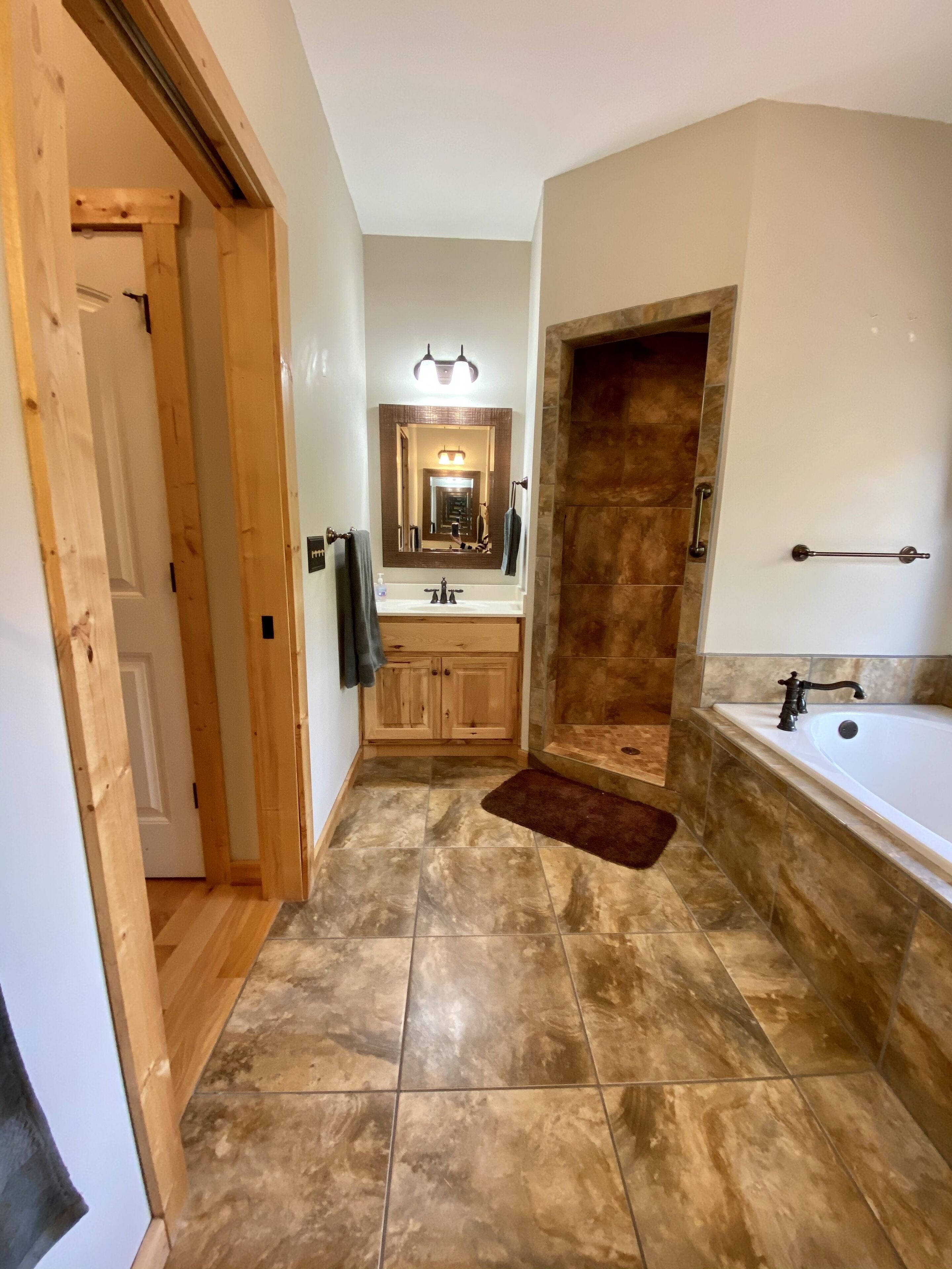 A modern bathroom with a large mirror, a bathtub, and a sink.