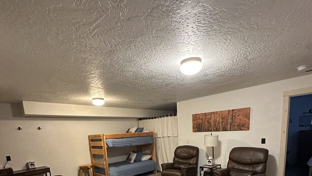 Una habitación compacta con una cama litera, dos sillones de cuero, un sof á, una mesita y una lámpara.