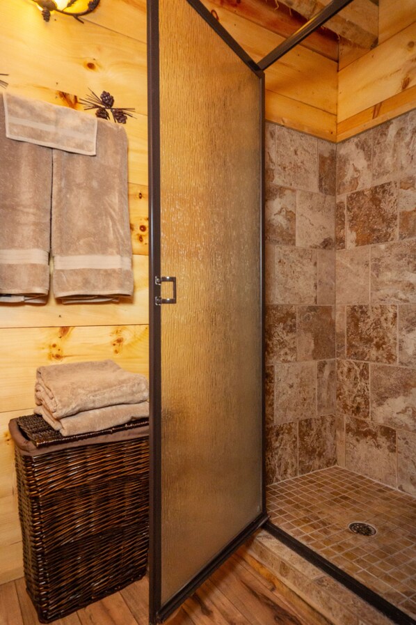 Un intérieur en bois avec un espace douche, des serviettes et un panier en osier.