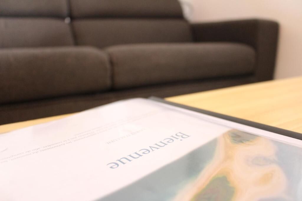 A brochure or pamphlet on a table with a blurred background of a dark-colored sofa.