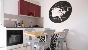 Une cuisine moderne avec des meubles de rangement rouges, un four noir et une table à manger avec quatre chaises.