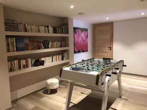Relax in a space designed for reading and recreation, featuring a bookshelf and foosball table.