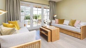 A spacious living room with a sofa, chairs, a coffee table, and a large sliding glass door leading to an outdoor area. - Kliffhoog 5 from A&M - Kliffhoog 5 (Kampen (Sylt))