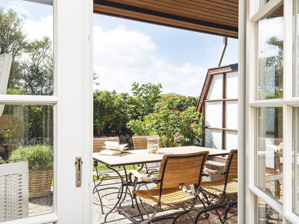 An open patio with a table and chairs, a book, and a glass of water.