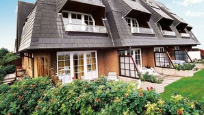 A house with a steeply pitched roof, multiple windows, and a well-maintained garden. - Kliffhoog 5 from A&M - Kliffhoog 5 (Kampen (Sylt))
